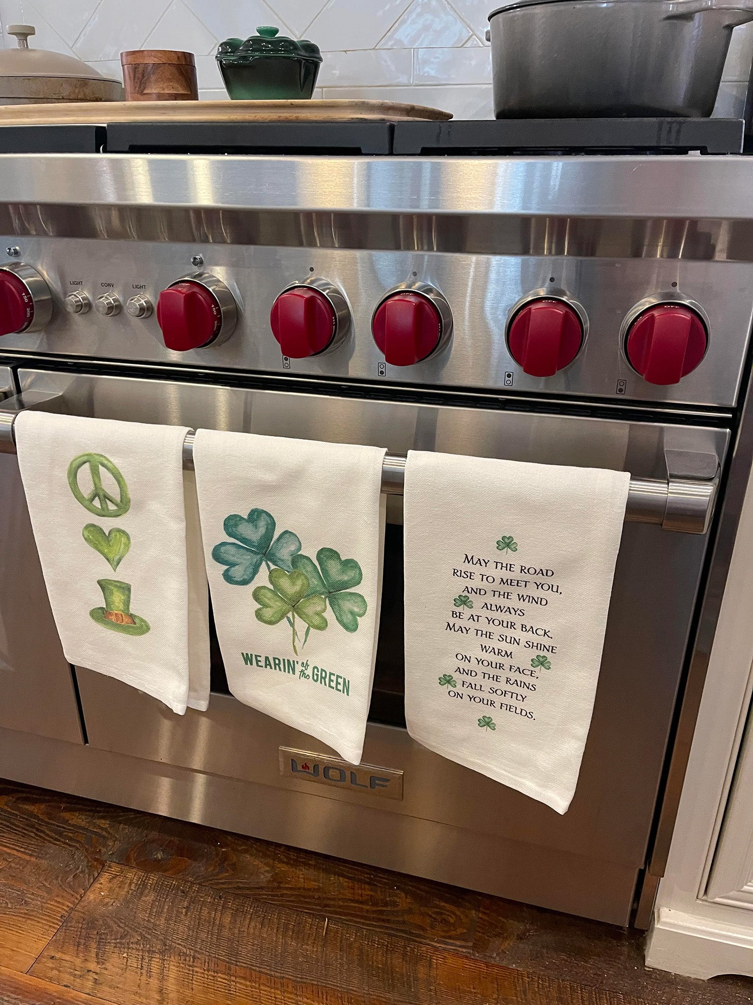 Three St. Patrick's Day kitchen Towels hanging in front of stove.